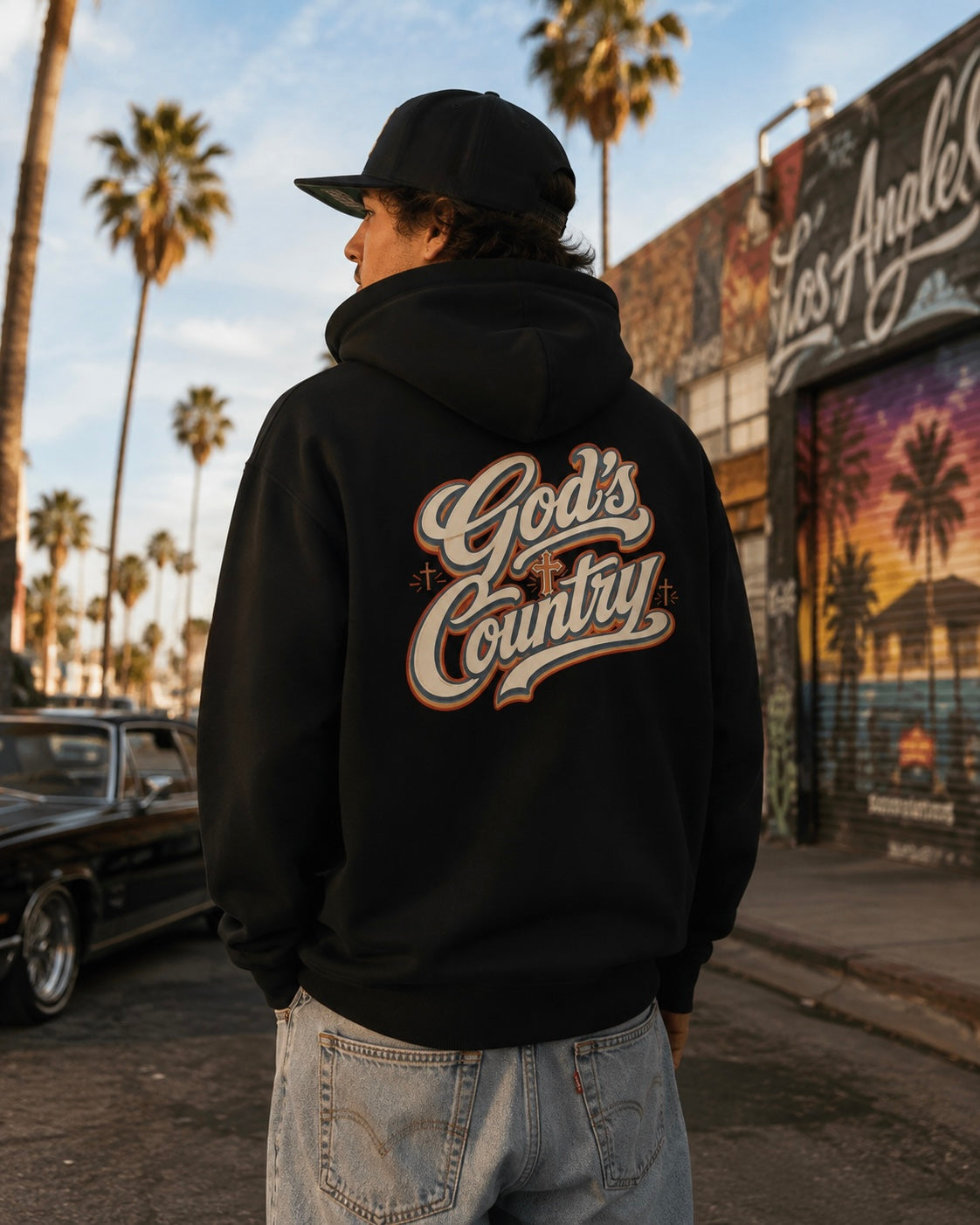 Black hoodie worn outdoors, with large 'God's Country' back graphic and hood